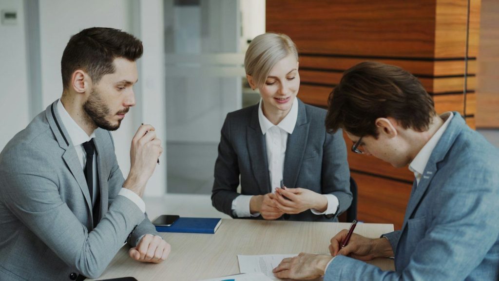 Attorney reviewing a contract with two clients at a table